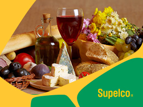 A colorful food arrangement on a table featuring cheese, bread, wine, olives, and fruits, with yellow and green graphic shapes in the background and the word “Supelco” in the corner.