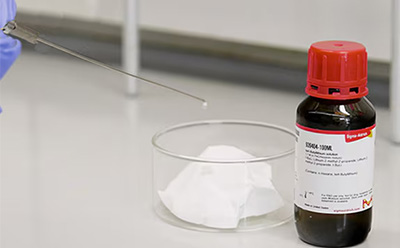 Bench-Stable Non-pyrophoric Butyllithium Reagents Laboratory vial with a red cap beside a small pile of white powder on a glass surface.
