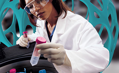 Amicon® featuring scientist in lab Photograph of a scientist holding 15 mL Amicon® device with gloved hand placing into a centrifuge.