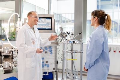 Scientists Evaluating Protein A Chromatography Processes Two scientists discussing chromatography equipment in a laboratory environment.