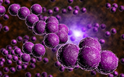 A close-up view of a chain of spherical purple objects against a blurred background of similar objects. The spheres are clustered together in a string-like formation, reminiscent of a molecular structure or bacteria chain. Each sphere has a textured surface, giving it a realistic appearance. The background consists of numerous smaller, out-of-focus spheres creating an impression of depth and multitude. There is a bright light source in the center background that illuminates the scene with a soft glow, enhancing the purple hue