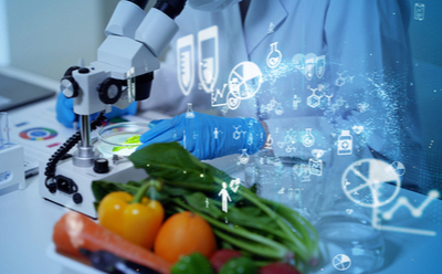 专注于食品科学研究的实验室设施。该图片显示了一只处理培养皿的机器臂，带有分子结构和科学符号的全息投影。在前景中有各种新鲜蔬菜和水果，包括桔子和绿叶蔬菜，表明实验室进行的是天然食品性质的研究。