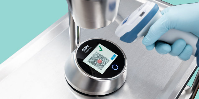 <p>Prepararse para el futuro</p> Una mano con un guante azul escanea un código QR en un aparato de laboratorio de acero inoxidable con un escáner portátil.