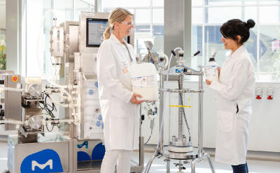 Mobius® Chrom 20 chromatography system and chromatography column A Mobius® Chrom 20 chromatography system and chromatography column in a lab environment with two female scientists, one of them handling a bottle of chromatography resin.