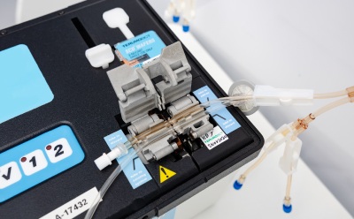 NovaSeptum® SURe for ACT accurate volume syringe assembly mounted in a black holder, with connected tubing and sterile connectors arranged on a white laboratory surface NovaSeptum® SURe for ACT accurate volume syringe assembly mounted in a black holder, with connected tubing and sterile connectors arranged on a white laboratory surface