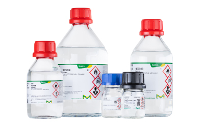 Assorted PFAS-tested solvents in clear bottles with red caps and hazard labels arranged together.