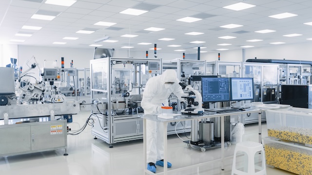 Shot of sterile pharmaceutical manufacturing laboratory where scientists in protective coverall's do research, quality control and work on the discovery of new medicine