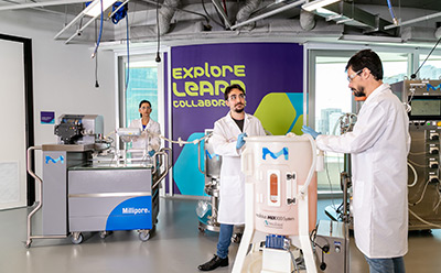 Scientists in a lab setting with manufacturing equipment around