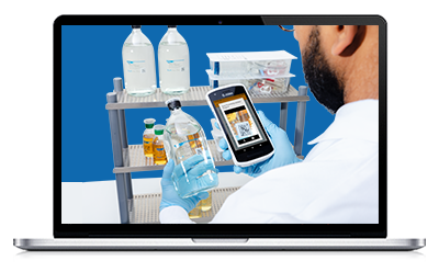 M Trace Webinar A person in a white lab coat holding a smartphone while observing a cart with various laboratory bottles against a blue backdrop.