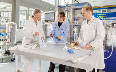 Navigating EU GMP Annex 1: Effective strategies for single-use challenges in bioprocessing Three scientists stand around a workbench evaluating single-use bioprocessing assemblies and sterile fluid-handling components beside manufacturing equipment in a pharmaceutical facility.