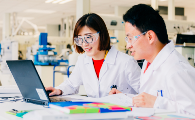 AIDDISON Service Page hero Two scientists in lab coats and safety glasses reviewing data on a laptop in a modern laboratory