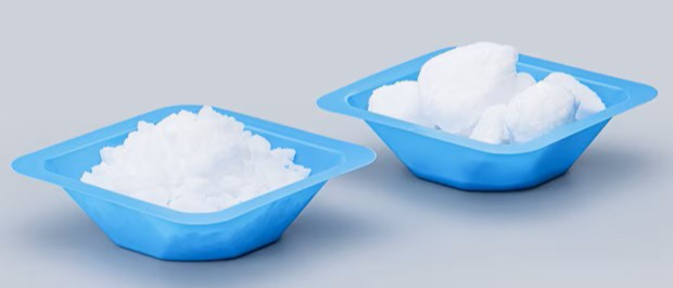 Side-by-side comparison of free-flowing EMSURE® granulated salt and conventional powdered salt showing larger granules and a caked powder form in separate blue trays.