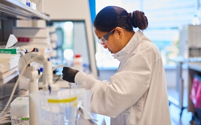 T7 Promoter System Lab worker pipetting at a work station.