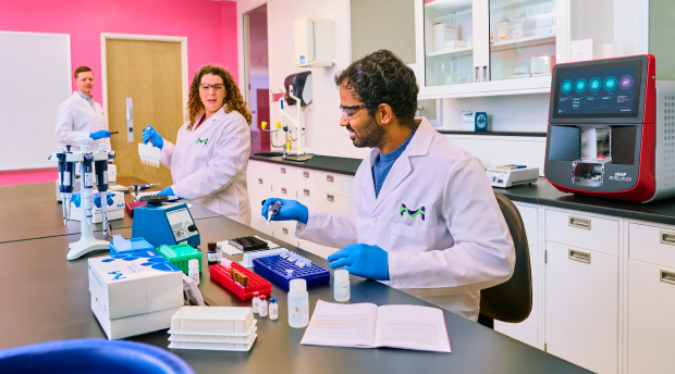 Three scientists in a lab performing immunoassay work on the Luminex® xMAP® INTELLIFLEX® system, with other instruments in the background.