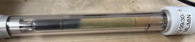 Transparent OMI® gas purifier tube with visible color change along the sorbent bed, indicating contaminant adsorption during operation.