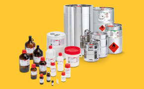 Assorted laboratory chemical containers—glass bottles, plastic bottles, cans, and stainless-steel drums—with red caps and hazard labels on a yellow background.