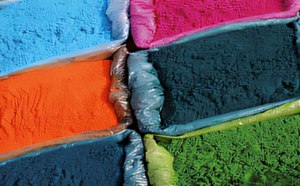 Primer plano de varios polvos de colores dispuestos en bolsas, con tonos vibrantes de azul, rosa, naranja, verde y azul oscuro.