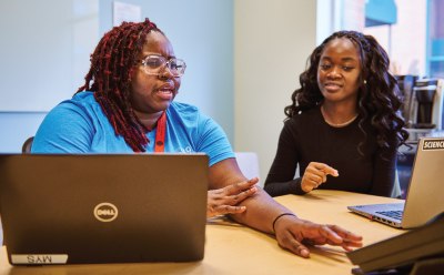 Dos mujeres sentadas en una mesa con ordenadores portátiles, dedicadas a trabajo en colaboración sobre navegación por la industria regulada. Dos mujeres sentadas en una mesa con ordenadores portátiles, dedicadas a trabajo en colaboración sobre navegación por la industria regulada.