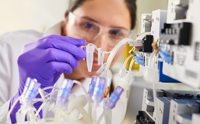 Woman collecting a small volume sample from Mobius Breez bioreactor
