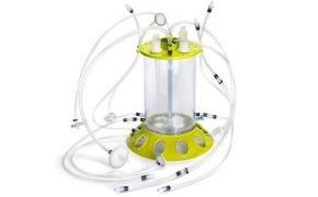 Mobius 3L Bioreactor Biorreactor Mobius® iFlex 200 l en modo de perfusión. Cilindro transparente con una base amarilla y, en la parte superior, tubos transparentes que salen por todas partes.
