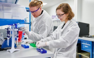 Laboratory Technicians Working with Equipment Two laboratory technicians in white coats working at a lab bench, using scientific equipment and preparing samples.