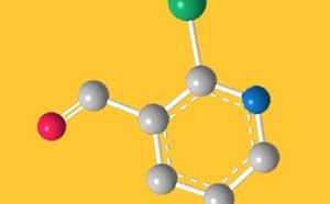 Ilustración de una estructura molecular tridimensional sobre fondo amarillo. El modelo muestra una estructura anular con esferas grises que representan átomos de carbono, conectadas por enlaces blancos. Varias esferas de colores representan diferentes átomos: una esfera roja (posiblemente oxígeno), una esfera verde y una esfera azul. La disposición pone de relieve la conectividad y la geometría moleculares.