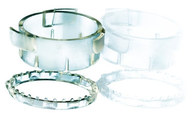 Cuatro anillos de pl&aacute;stico transparentes y semitransparentes de diferentes tama&ntilde;os y dise&ntilde;os, algunos con pernos met&aacute;licos o estructuras en forma de dientes, dispuestos sobre un fondo blanco. Parecen ser componentes posiblemente utilizados en entornos mec&aacute;nicos o de laboratorio.