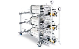Equipo de filtración con múltiples filtros cilíndricos conectados por tuberías metálicas, colocados sobre un fondo blanco.