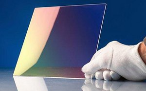 Imagen de un vidrio de calcogenuro bidimensional sostenido en posición vertical por una mano enguantada para mostrar el recubrimiento.