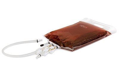 Vegetable Peptone Broth for Media Fill Trials. A sealed, flexible plastic bag filled with a brownish-red liquid. The bag is displayed against a white background. It has a clear, labeled port and attached tubing with a clamp to control the flow of the liquid.