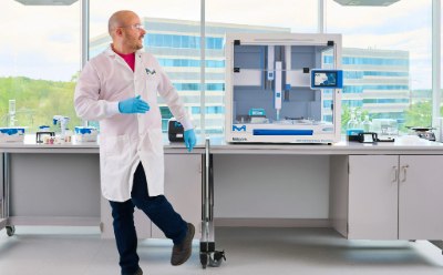 Scientist walking away from the bench, turning back to look at the AAW™ workstation