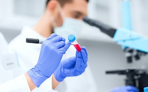 Trabajador de laboratorio rellenado una etiqueta en un tubo de ensayo.