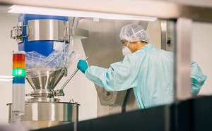 Técnico que supervisa un biorreactor de procesamiento químico: un profesional con ropa protectora que controla meticulosamente un biorreactor de acero inoxidable, el cual forma parte integral del procesamiento downstream y la formulación en la industria química, dentro de un entorno de sala limpia.