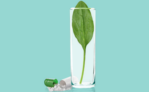 La imagen representa un vaso de agua transparente que contiene una sola hoja verde, rodeado de pastillas y cápsulas dispersas. Una de las cápsulas está abierta, revelando su contenido en polvo.