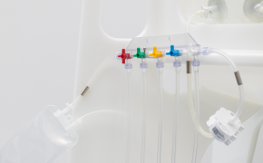 Un colector médico con cinco válvulas de colores: rojo, amarillo, verde, azul y púrpura. Cada válvula está conectada a un tubo transparente, que se extiende desde el colector.