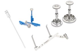 Conjunto de instrumentos médicos, como jeringas y otras herramientas, ordenados cuidadosamente sobre un fondo blanco. Pueden verse un instrumento largo y delgado con un bucle en el extremo, dos tipos de jeringas, una con un émbolo azul y otra con una estructura compleja, e instrumentos metálicos que parecen ser parte de un aparato para procedimientos médicos especializados. También hay un instrumento metálico con un diseño angular y algo similar a una abrazadera en su extremo, lo que sugiere su uso en tareas médicas de precisión.