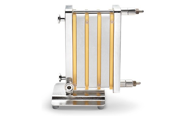 Pellicon® Single-Pass TFF Dispositivo de filtración por flujo tangencial caracterizado por múltiples tubos amarillentos alineados verticalmente y en paralelo, conectados a un marco metálico, con cuatro varillas que aseguran la estructura y una base metálica robusta para estabilidad durante el funcionamiento.