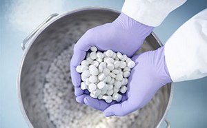 Comprimidos recién producidos en las manos enguantadas de un trabajador farmacéutico