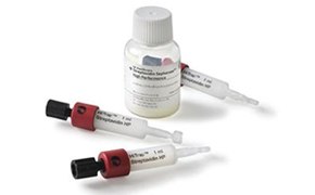 En la imagen se observa una botella blanca pequeña con medicamento y tres jeringas HiTrap Protein G HP utilizadas para la purificación de proteínas. Las jeringas tienen un cuerpo blanco, tapas rojas y émbolos negro. La botella y las jeringas tienen etiquetas con instrucciones de administración.