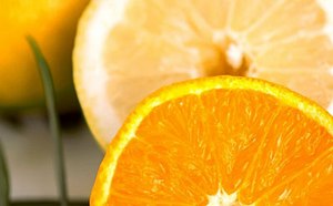 Un vibrante primer plano de una jugosa rodaja de naranja con una de limón detrás, destacando la textura fresca y apetitosa de los cítricos.