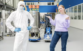 Closed Processing for Biomanufacturing Two scientists, standing in a lab, a male in bunny suit, a female wearing casual clothes