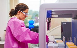 Scientist placing a microplate on an automated workstation.