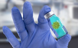 Gloved hand holding ampule of a novel therapeutic.