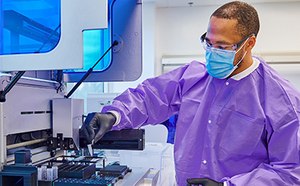Male lab technician with protection clothes doing some tests by using a machine.