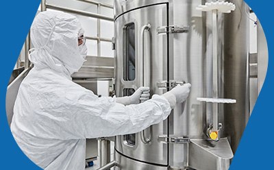 Manufacturing operator in PPE operates a 1,000L single-use bioreactor during AAV production