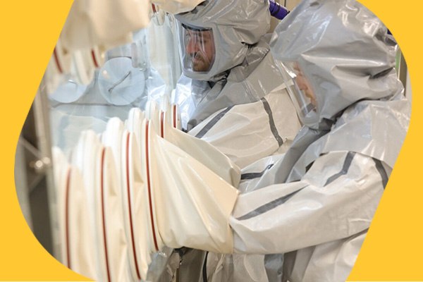 Safe handling of highly potent APIs in isolator by two operators in protection suits