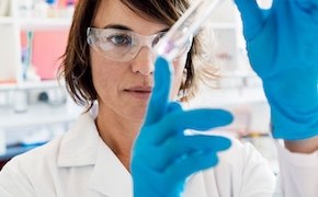 Scientist in a lab carefully looking at a test tube that she is holding in her hands