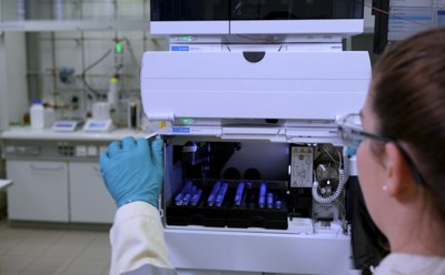 Clinical Lipids CDMO Services Lab scientist is loading analytical samples into a High-Performance Liquid Chromatography (HPLC) machine for monitoring the progress of chemical syntheses and ensuring the quality of the produced materials.