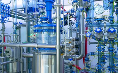 Commercial Lipids CDMO Services Close-up partial view of the Schaffhausen GMP pilot plant facility, featuring a 100-liter glass-lined reaction vessel and the glass-lined piping connected to and from the vessel.