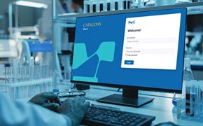 Un primer plano de una pantalla de ordenador que muestra una interfaz de inicio de sesión de &quot;Catalent&quot; con campos para el nombre de usuario y la contraseña. Se observan las manos de una persona sobre un teclado, con equipo de laboratorio en el fondo.